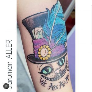tatuaje a color de gato Alicia en el pais de las maravillas en el brazo