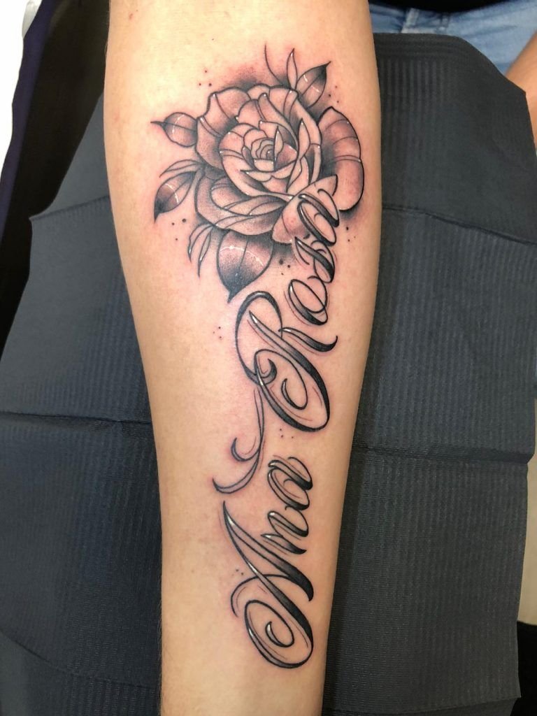Tatuaje estilo lettering con una flor en el antebrazo
