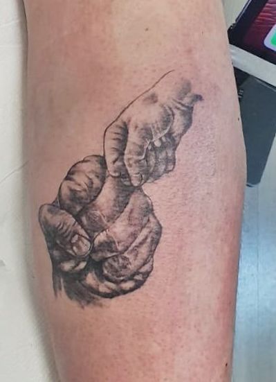 Tatuaje del puño de un adulto y el puño de un niño chocándose estilo realismo