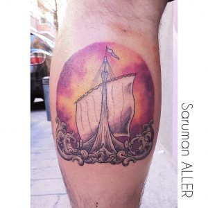 Tatuaje minimalista a color de un barco en el gemelo