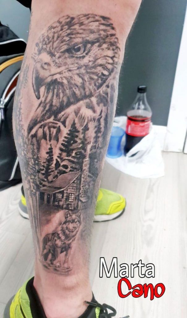 Tatuaje de un águila en un bosque con una casa y un lobo estilo realismo en la pierna