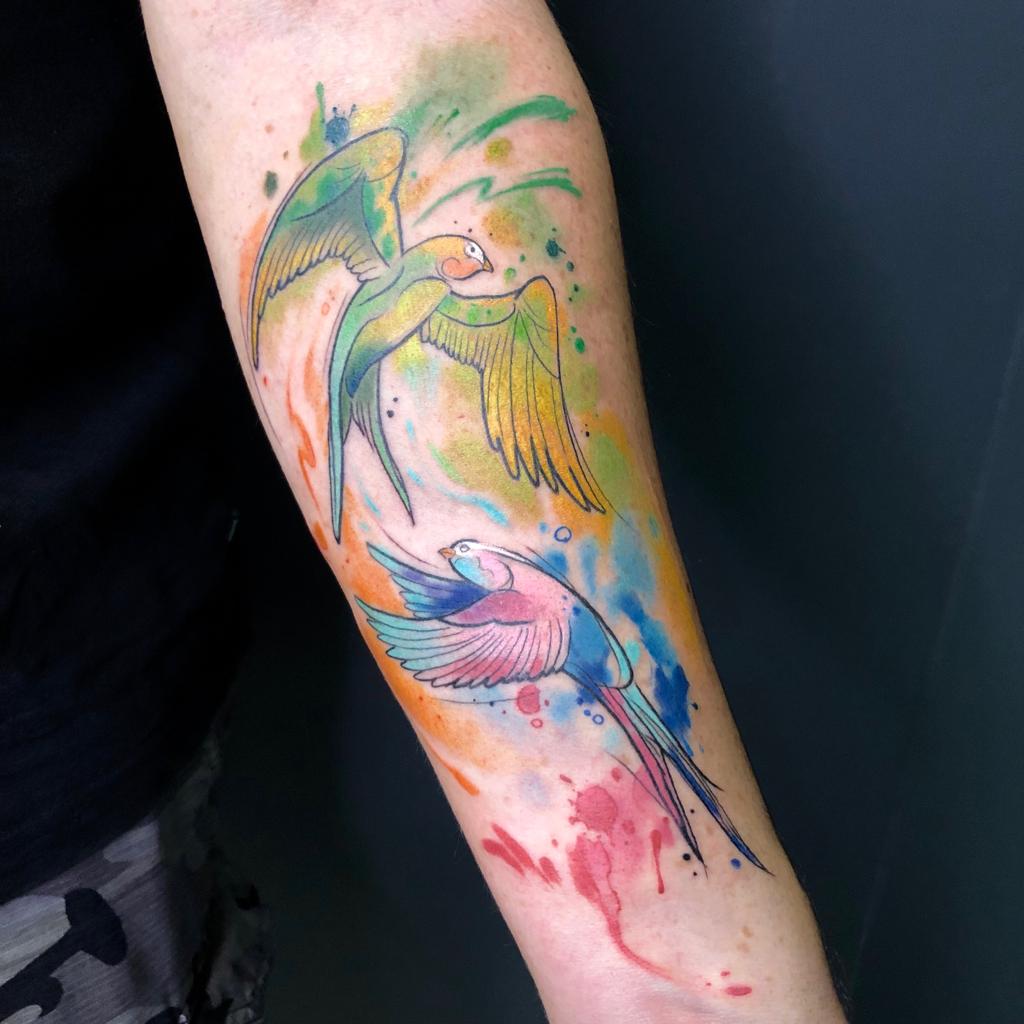 Tatuaje periquitos estilo watercolor en el antebrazo