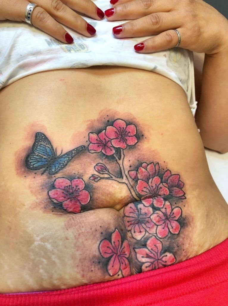Tatuaje flores con mariposa a color en el estomago