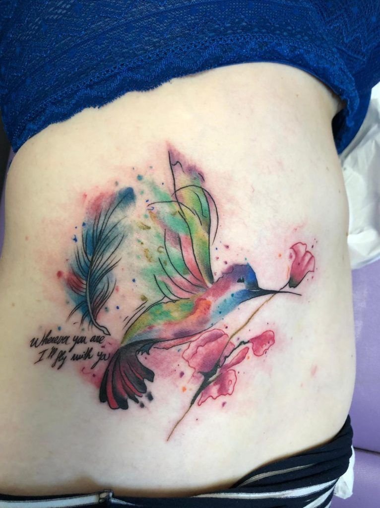 Tatuaje colibrí sosteniendo una rosa con lettering estilo watercolor