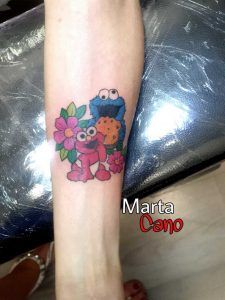 Tatuaje de los personajes de los dibujos animado plaza sésamo Lucas come galletas y Elmo estilo comic en el antebrazo