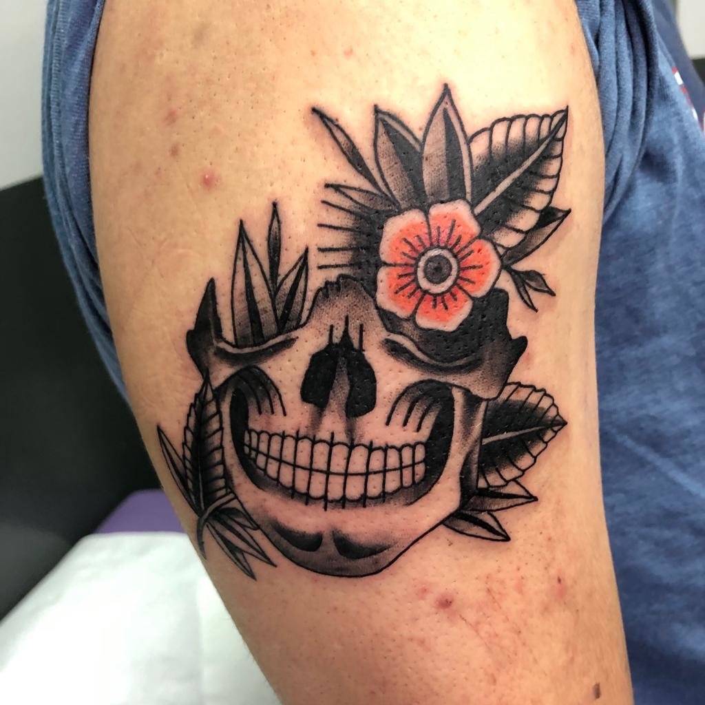 Tatuaje de la mitad de una calavera con una flor en el brazo