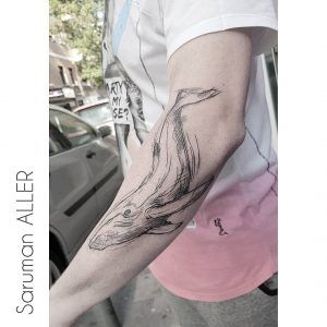 Tatuaje minimalista de una ballena en el brazo