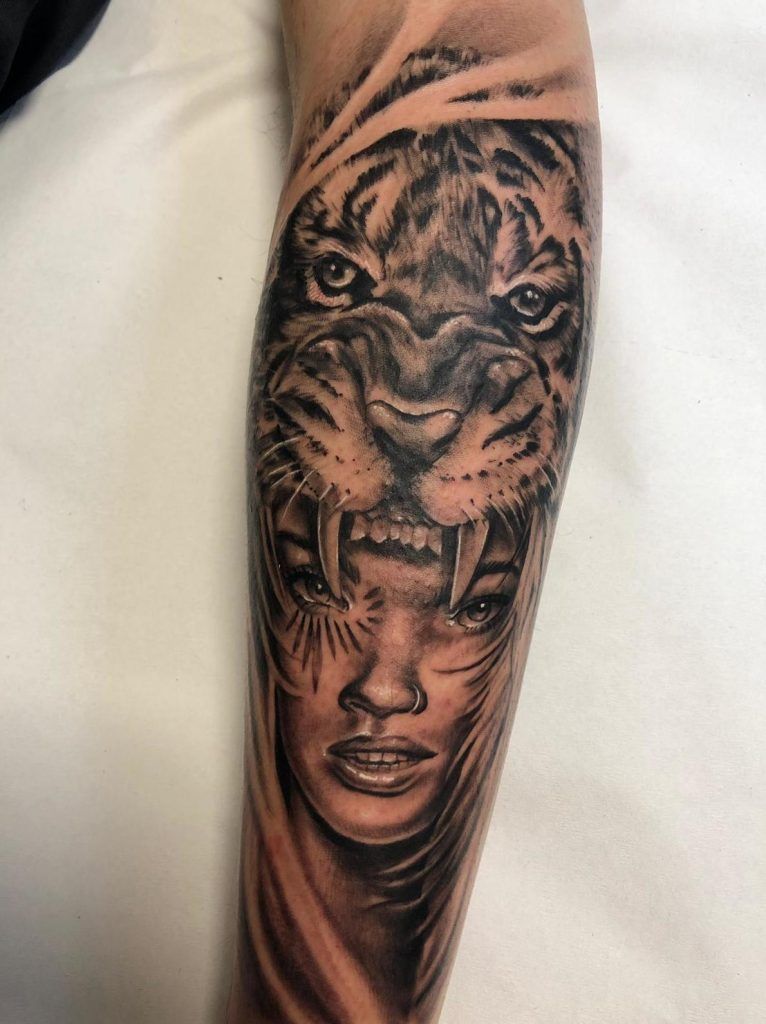 Tatuaje de en rostro de una chica con un tigre en la cabeza estilo realismo en el antebrazo