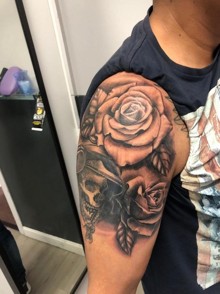 Tatuaje de dos rosas con una calavera estilo realismo en el brazo