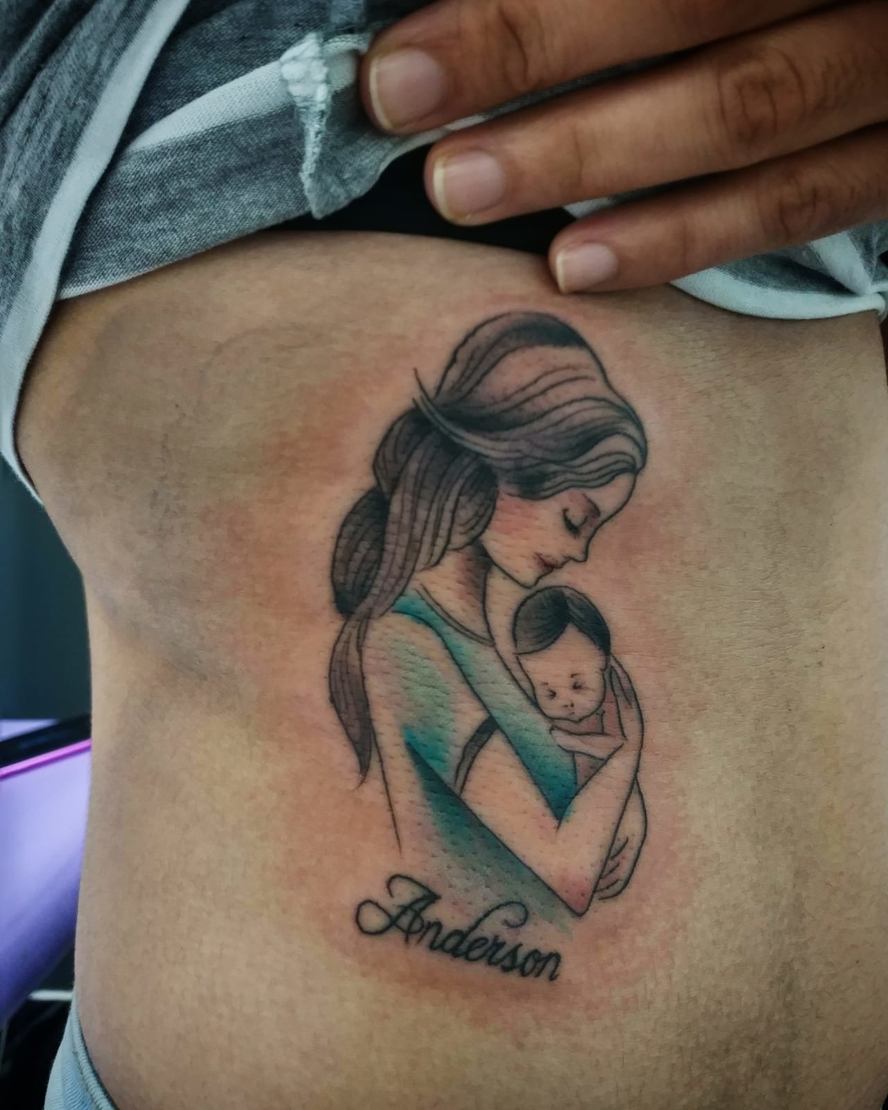 Tatuaje madre sosteniendo un bebe estilo minimalista con líneas finas