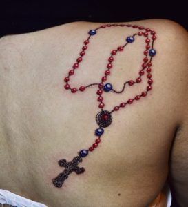 Tatuaje rosario en la espalda estilo realismo