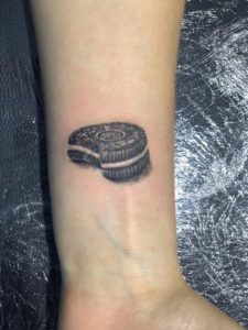 Tatuaje galleta oreo en el antebrazo estilo realismo