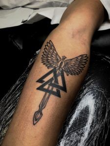 Tatuaje de espada con alas y tres triángulos en el antebrazo