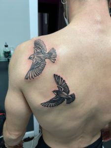 Tatuaje realista en la espalda de dos pájaros