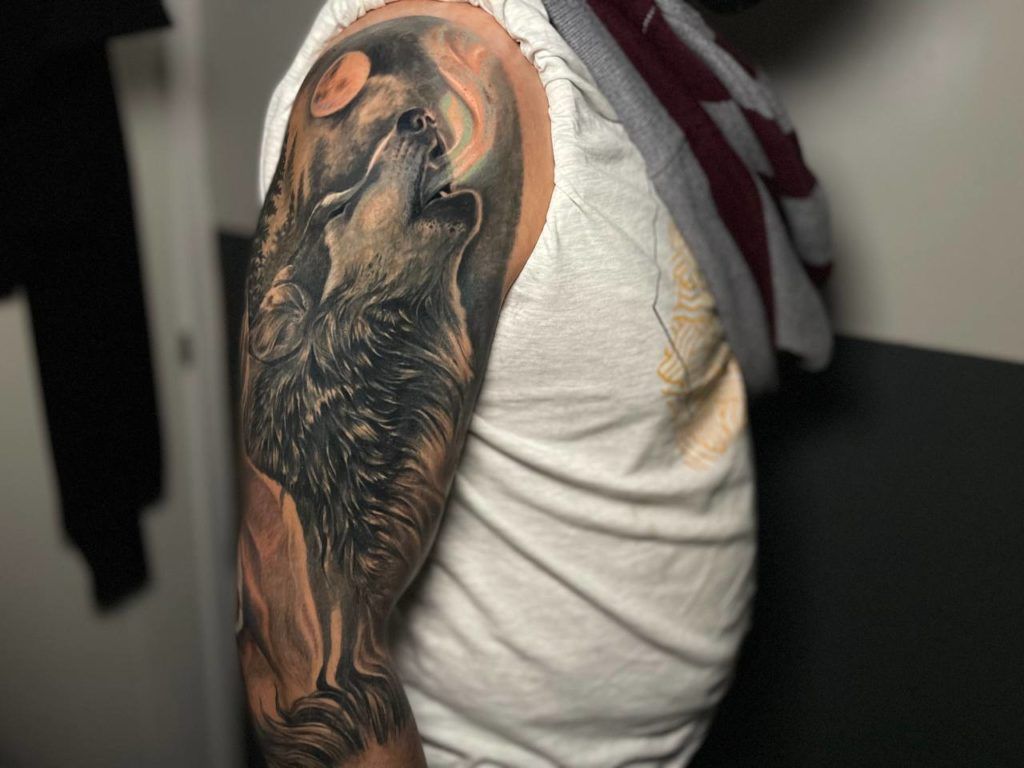 Tatuaje lobo maullando en el brazo estilo realismo