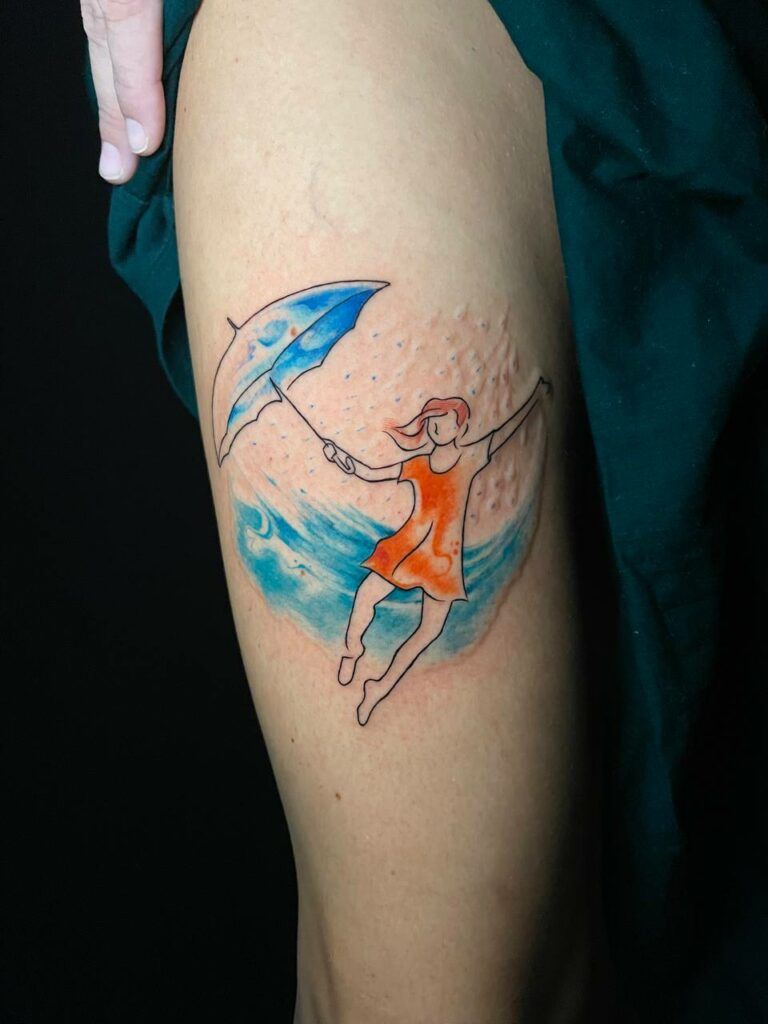 tatuaje de una chica bailando con un paragua realizado con líneas finas y efecto acuarela