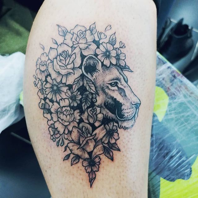 tatuaje de un león rodeado de flores y rosas