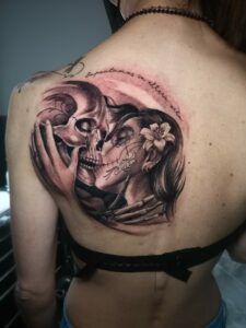 tatuaje de una pareja de catrinas besándose en la espalda