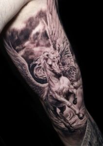 Tatuaje caballo con cuernos y alas en el brazo estilo realismo