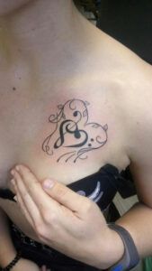 tattoo de notas musicales arriba del pecho mujer