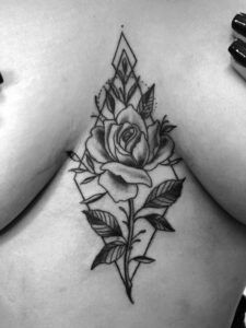 tattoo de una rosa estilo realista entre los senos