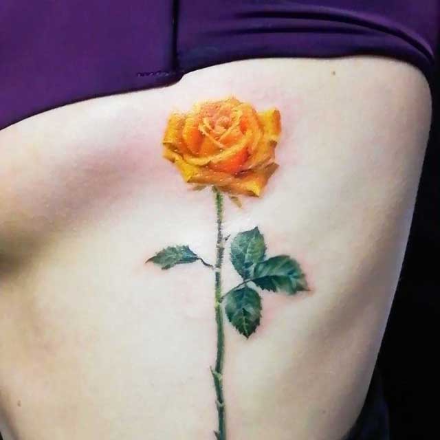 tatuaje de una rosa amarilla en las costillas