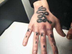 tatuaje en la mano de una serpiente y lettering