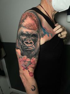tatuaje king kong con flores y detalles efecto acuarelas en el hombro de estilo realista