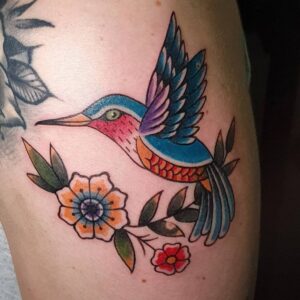 tatuaje Colibrí multicolor con flores en el hombro.