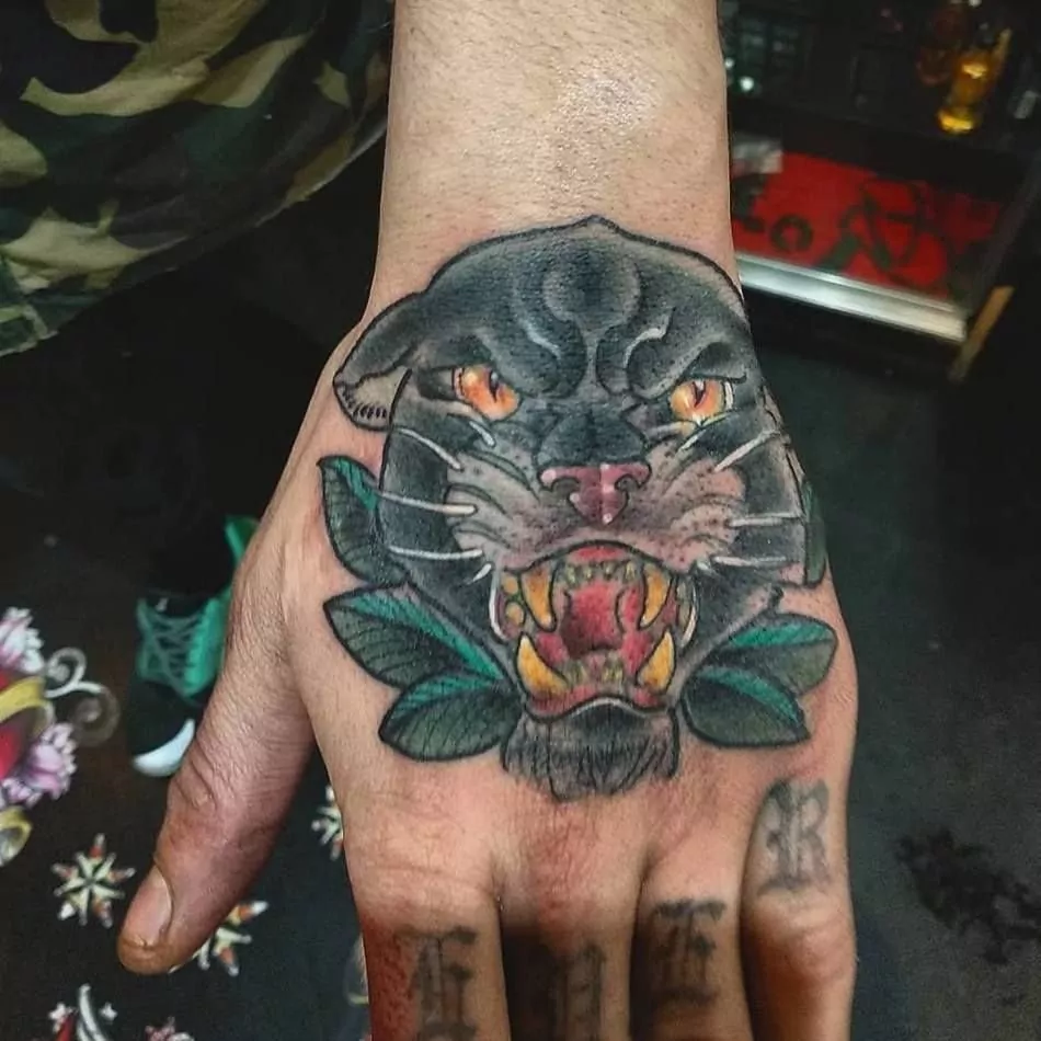 Tatuaje de una pantera negra estilo realismo a color en la mano