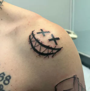 Tatuaje cara sonriente con ojos tachados o en equis