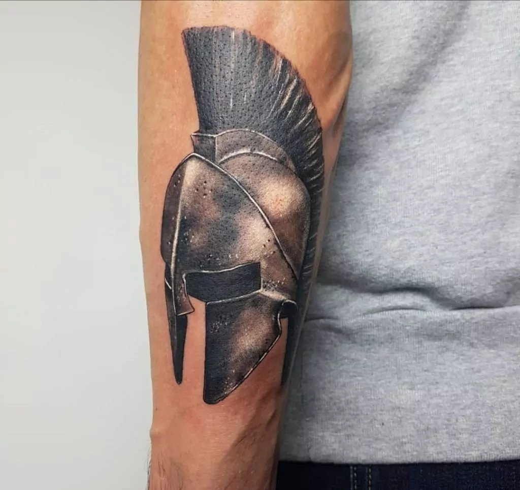 Tatuaje de un casco de un guerrero espartano en el antebrazo estilo realismo