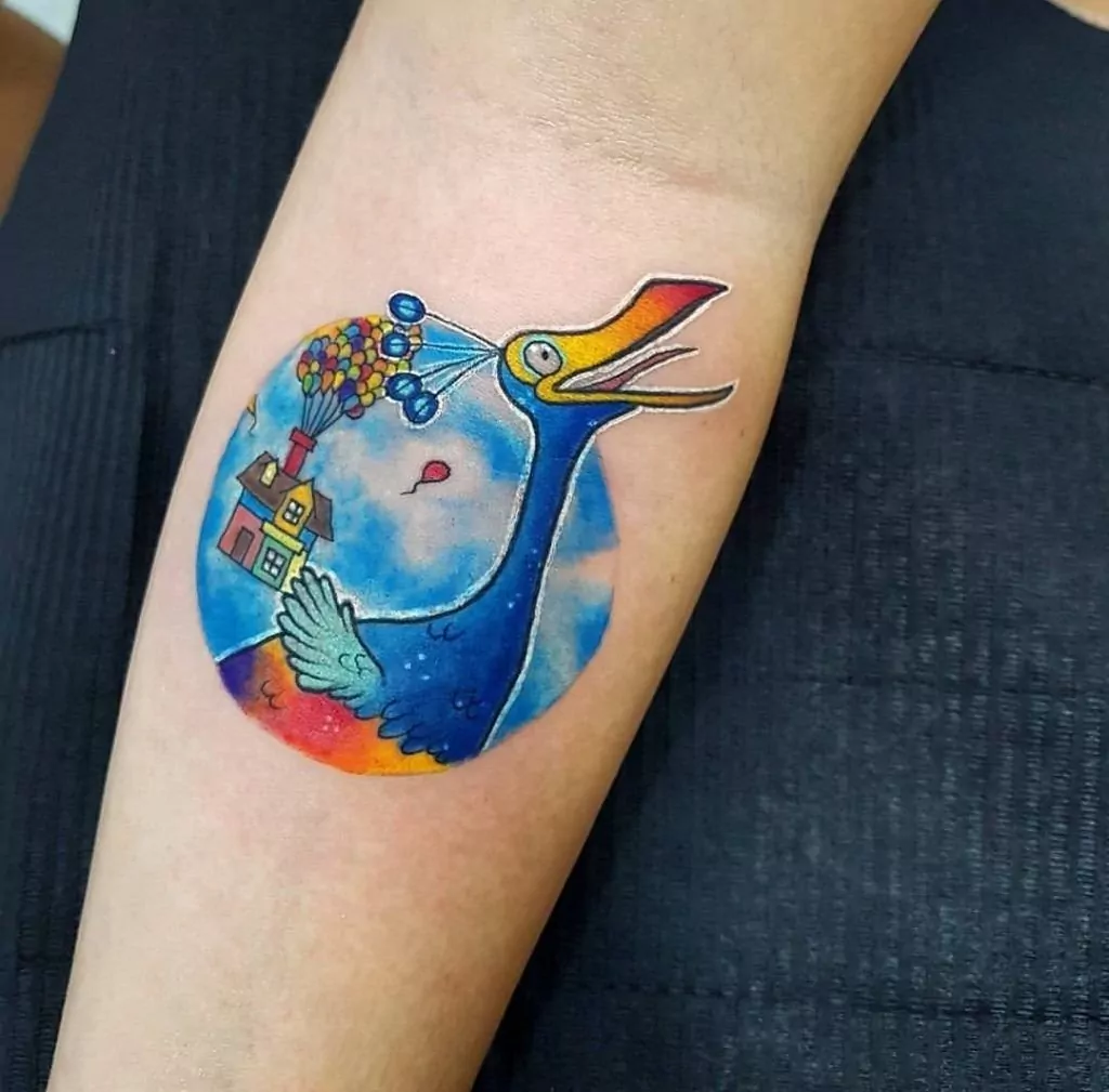 Tatuaje del pavo real y la casa flótate con globos de la película Up a color en el antebrazo