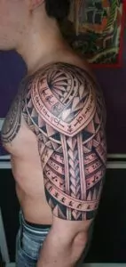 tatuaje egipcio de estilo maoríes en el brzo hombro y pecho