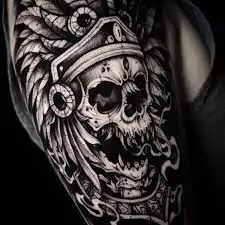 Tatuaje a blanco y negro de una calavera de la cultura maya en el brazo