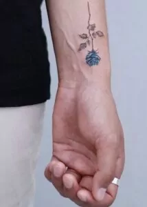 tatuaje minimalista flor azul en el brazo