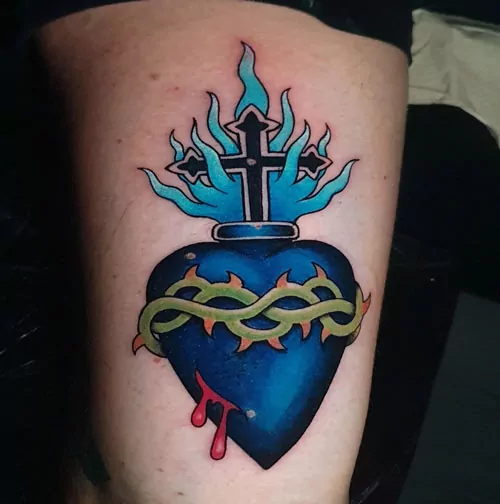 tatuaje de corazón azul con llamas en la pierna